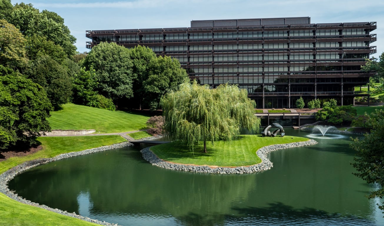 A John Deere központi épülete homlokzatának látképe a tóval és fákkal az előtérben