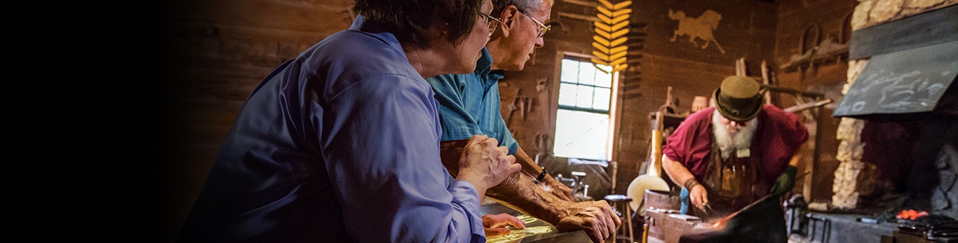 Idős pár néz egy kovácsot munka közben a Grand Detour (Illinois, Egyesült Államok) történelmi emlékhelyen
