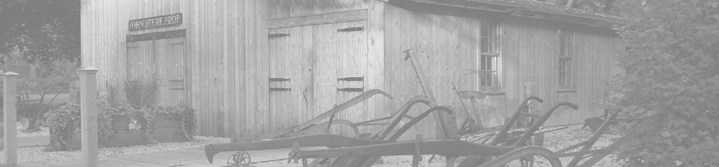 John Deere történelmi emlékhelyként működő eredeti kovácsműhelyének fekete-fehér tónusú fényképe zöld háttérrel
