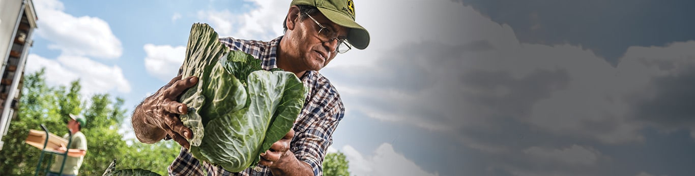 Védősisakos férfi egy munkaterületen, a közelben egy John Deere-gép.