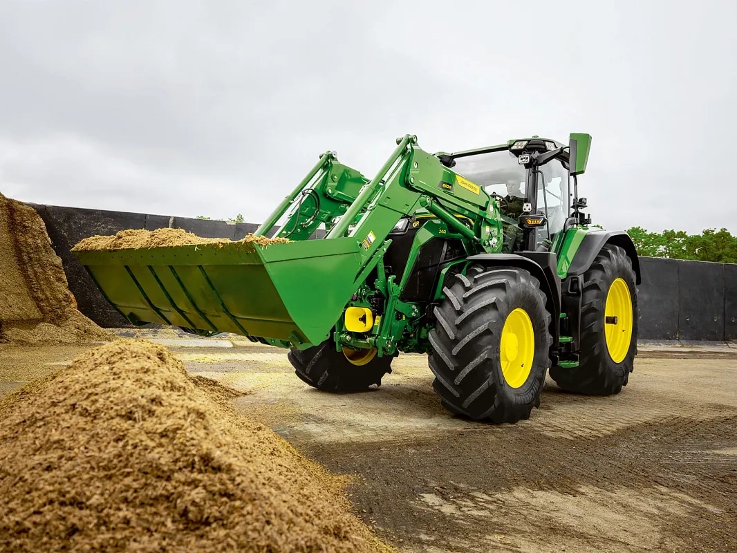 Homlokrakodó kanál silóval feltöltve egy John Deere traktoron az anyagmozgatási munkák során.