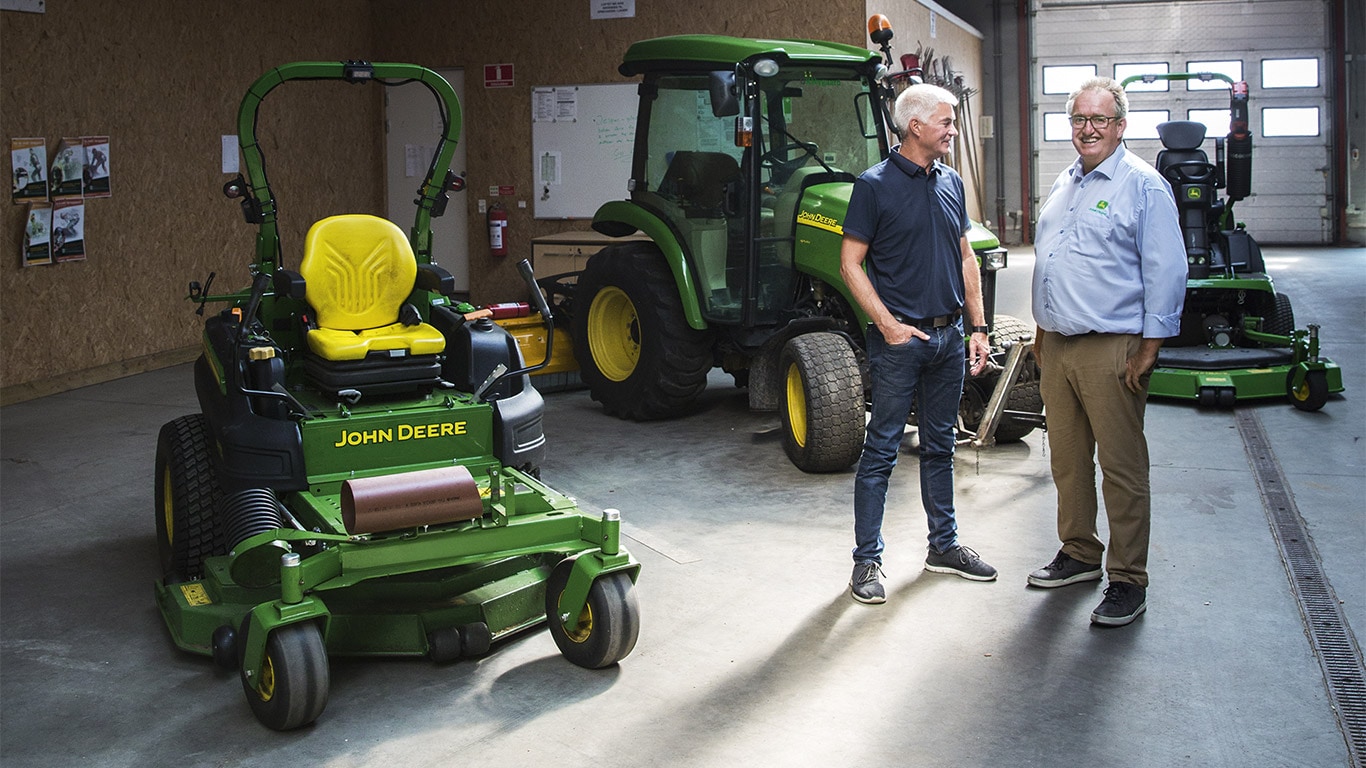 Nagyüzemi fűnyírás, gépcsarnok, helyben forduló fűnyíró, kompakt univerzális traktor, vásárló, márkakereskedő, beszélgetés