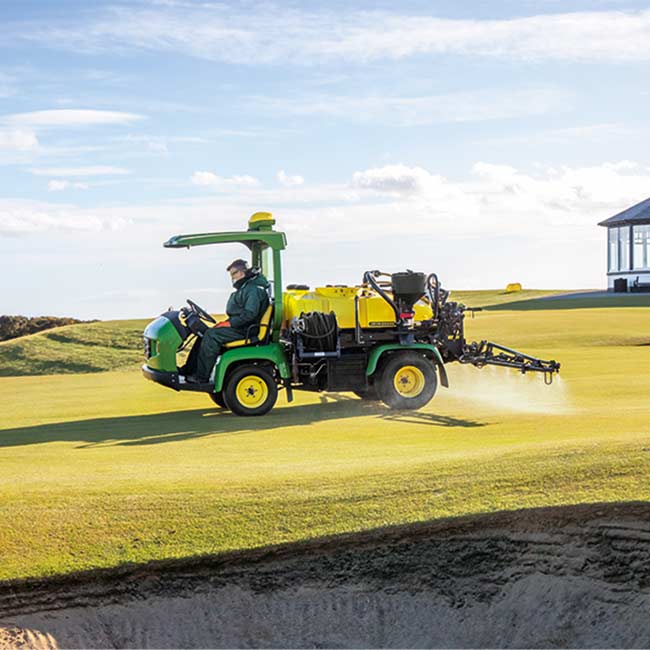 Golfpálya-karbantartó dolgozik a pályán John Deere permetezőgéppel