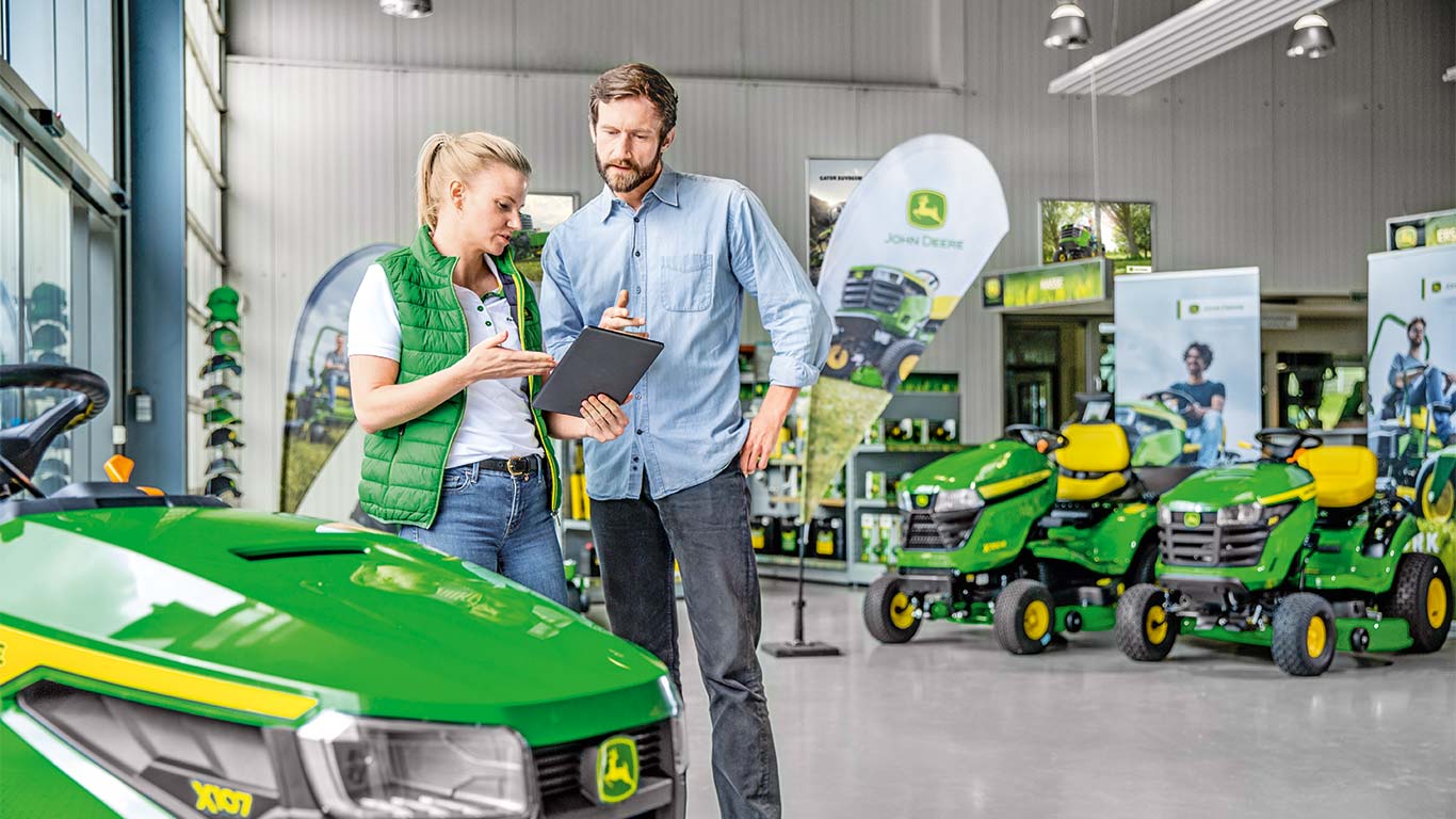 A John Deere-márkakereskedő tanácsot ad az ügyfélnek a John Deere-fűnyíró megvásárlásáról.