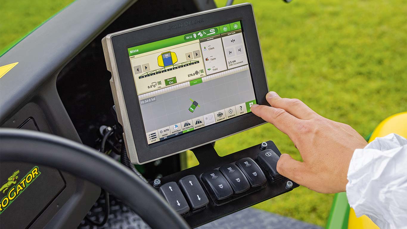 A John Deere fűnyíróján lévő kijelzővel a golfpálya karbantartója beállítja a gépet az aktuális feladathoz.