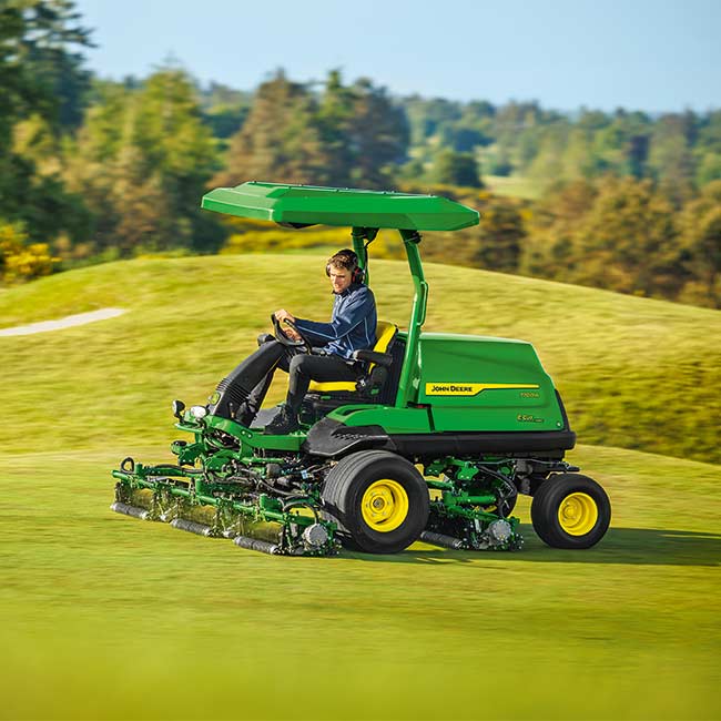 Golfpálya-karbantartó dolgozik a pályán John Deere golfpálya-fűnyíróval