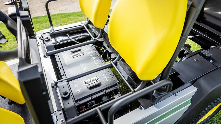 Közelkép a John Deere Gator GS elektromos többcélú járműben az élénk sárga ülések alá szerelt két lítiumakkumulátorról.