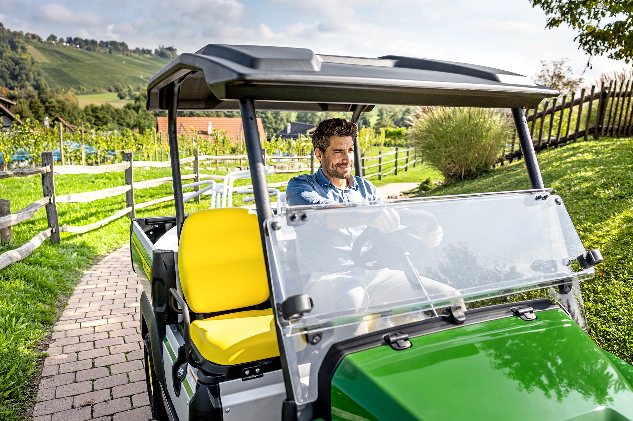 Közelkép a John Deere Gator GS belsejéről, sárga ülésekkel és kormánykerékkel Közelkép a John Deere Gator GS belsejéről, sárga ülésekkel és kormánykerékkel