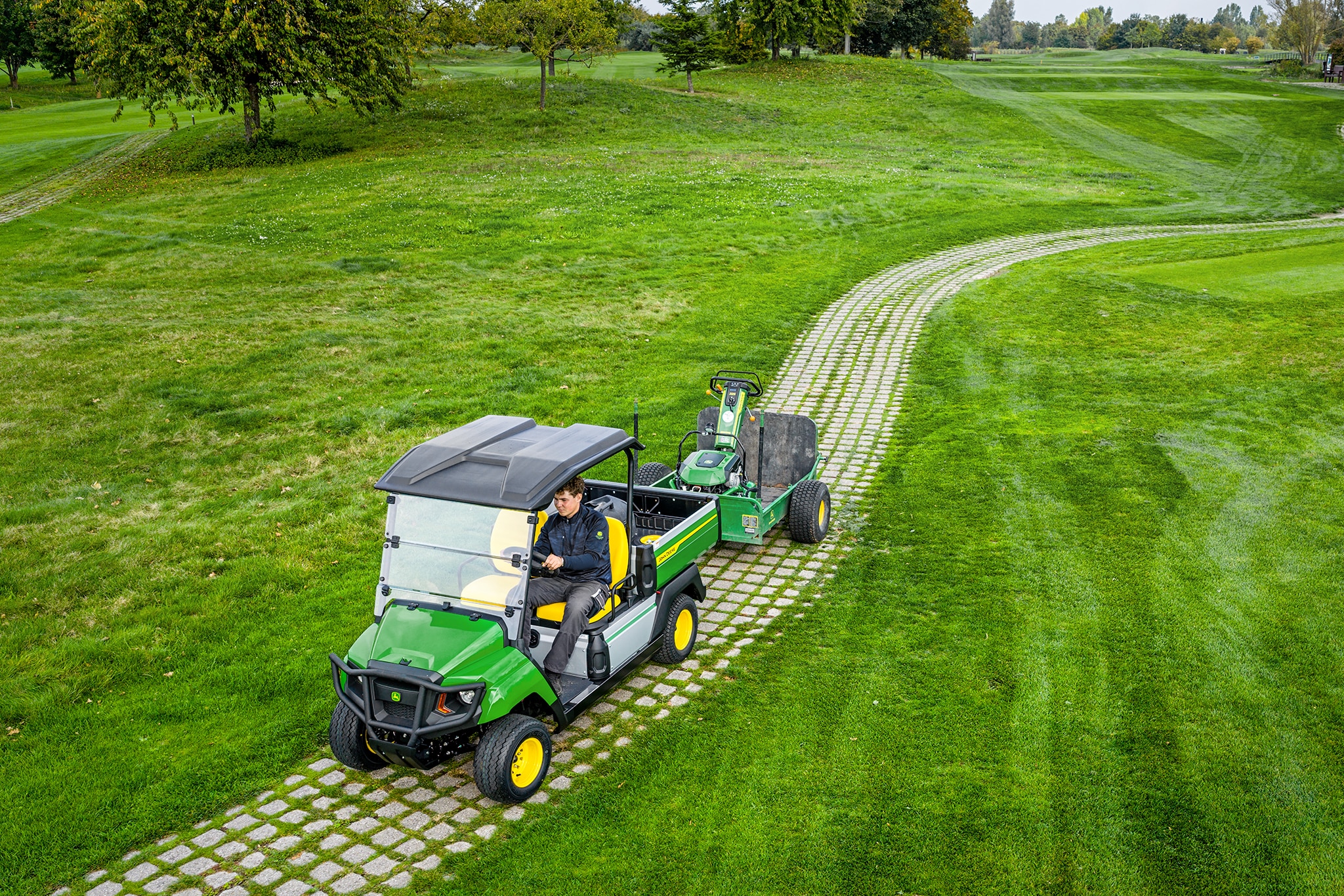 John Deere Gator GS vontató üzemben füves golfpálya útvonalon John Deere Gator GS vontató üzemben füves golfpálya útvonalon