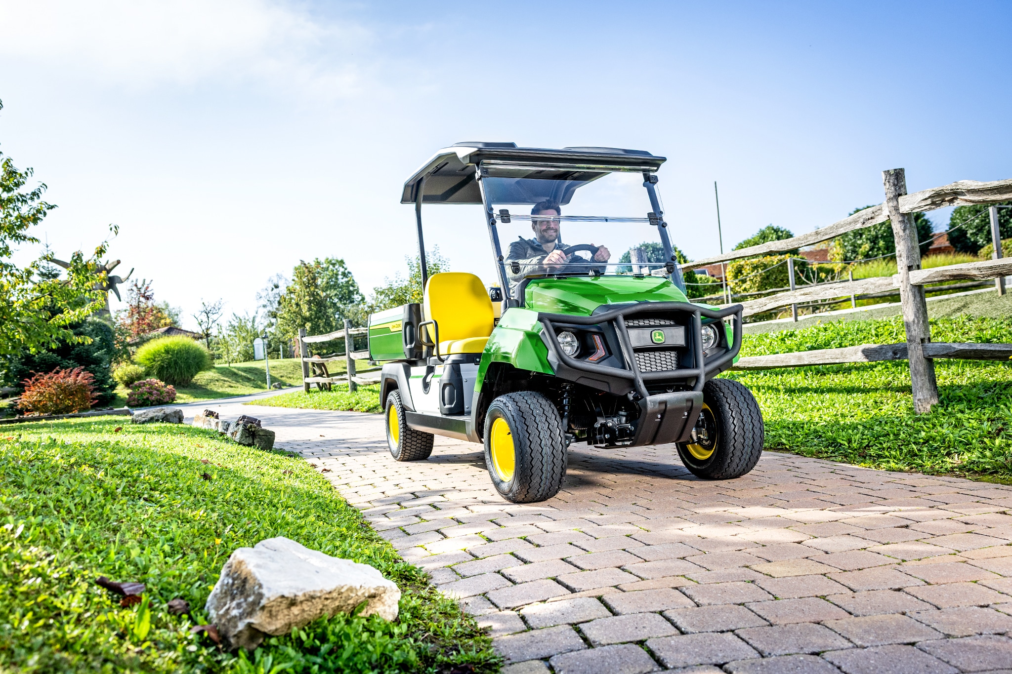 Gator GS többcélú jármű burkolt útvonalon halad egy parkosított területen Gator GS többcélú jármű burkolt útvonalon halad egy parkosított területen
