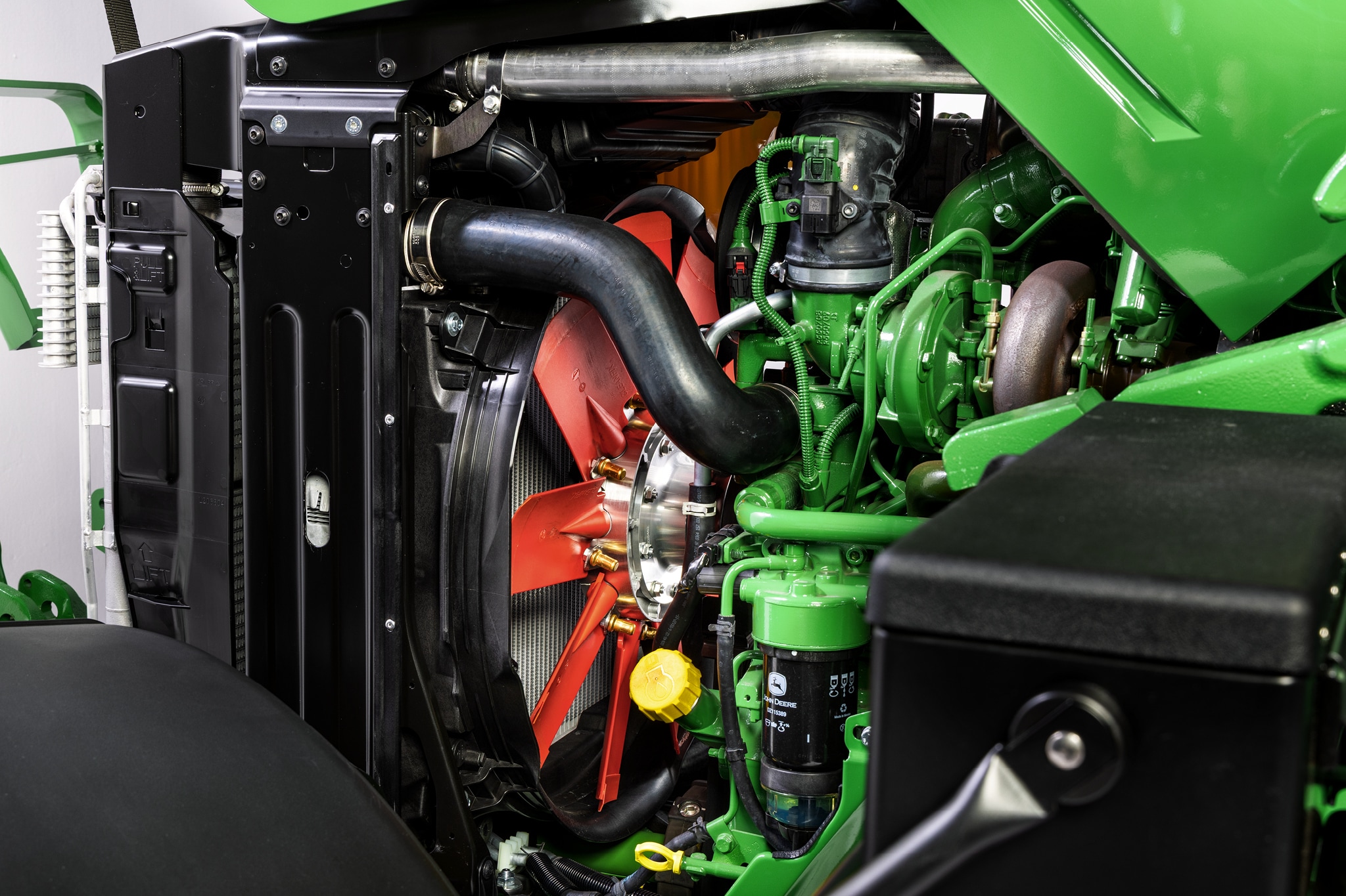 John Deere 6M sorozat motorterének közelképe, amely kiemeli a hűtőrendszert és a motor részegységeit.