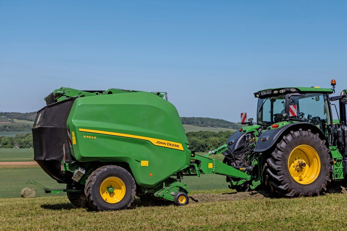 Egy John Deere 6R 185 traktor által vontatott John Deere V462R széna bálázás során